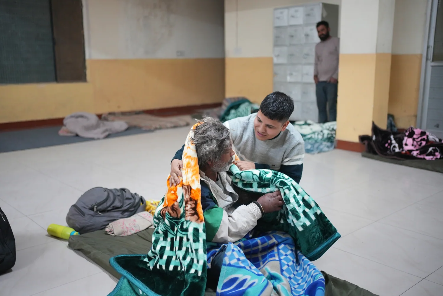 An individual blanket handover beside bedding inside the shelter.