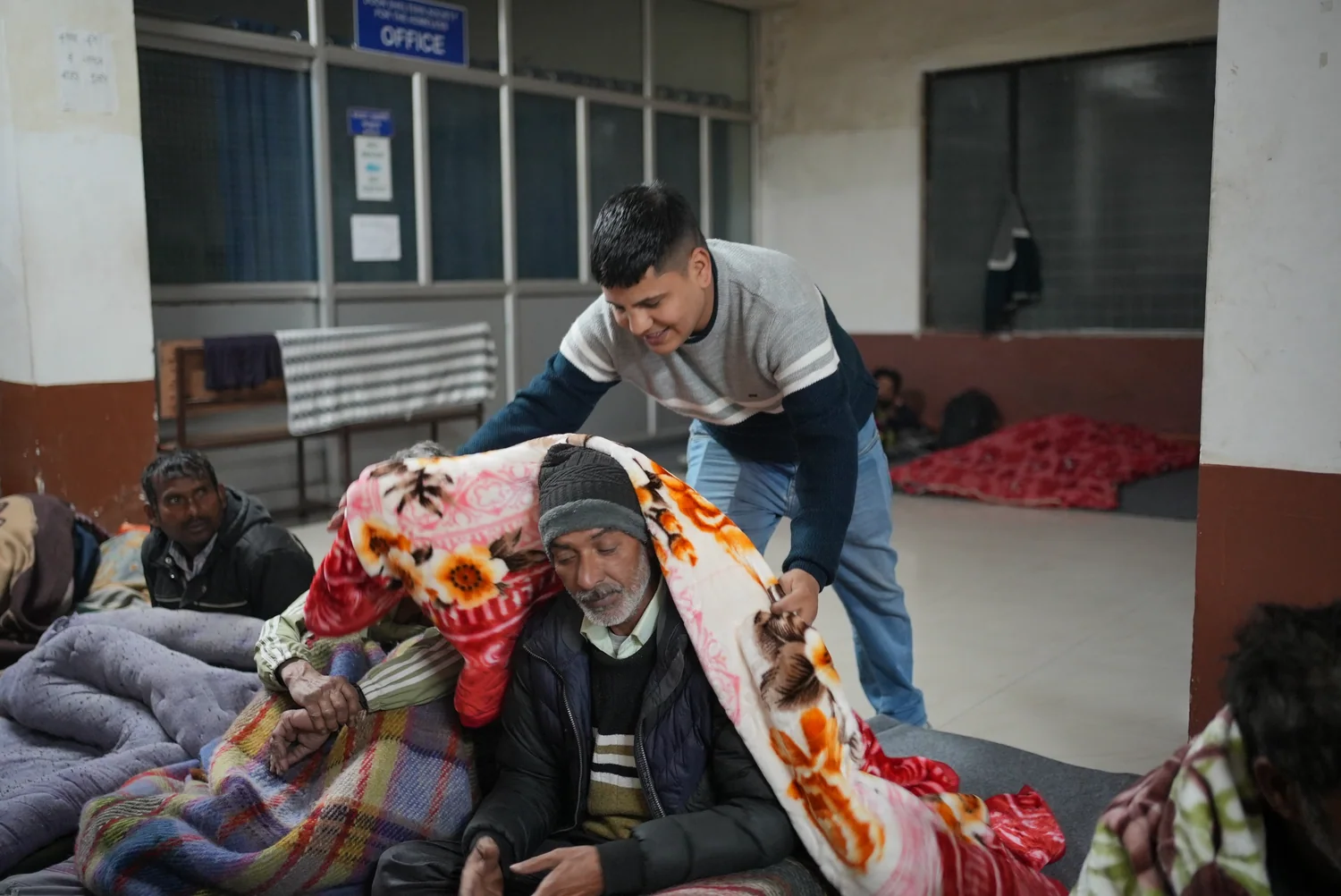 A warm blanket is arranged around a seated resident during the shelter visit.