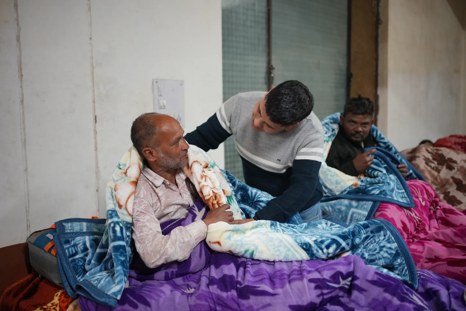 A team member sits with an older resident after a blanket handover.