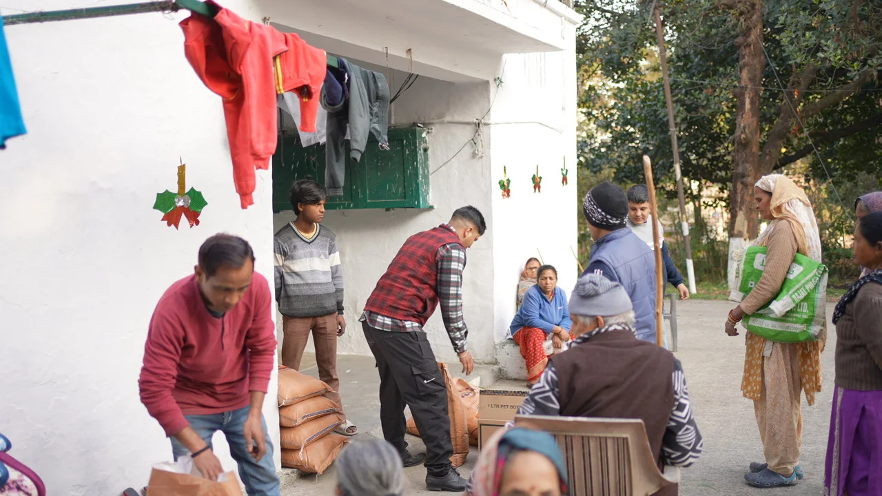 Residents and team members gather around ration bags and cartons prepared for distribution.