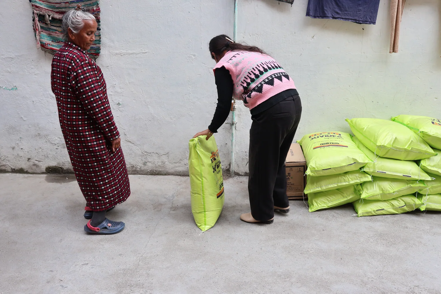 A team member presents a green flour bag to an older resident.