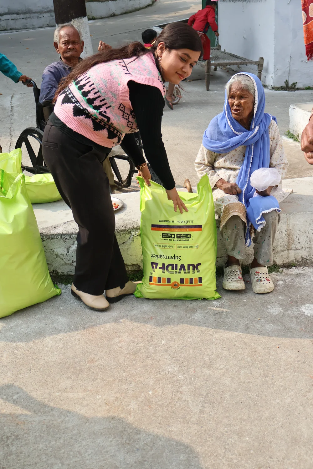 A flour bag is brought beside a seated older woman.