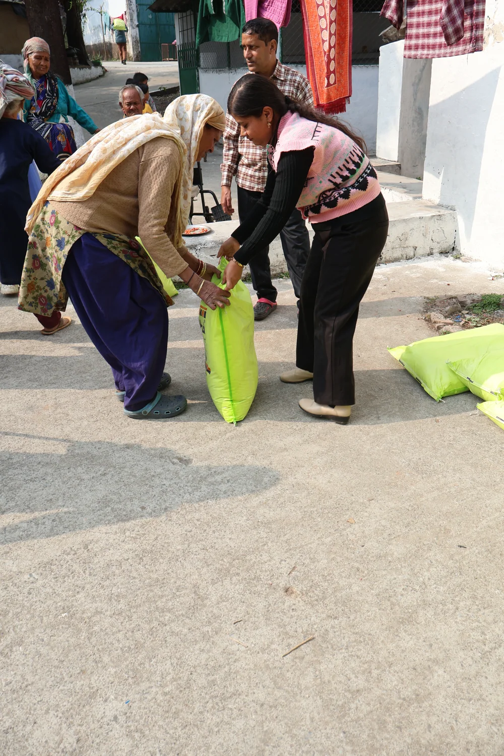 A team member assists an older resident using a walking stick at the ration handover.