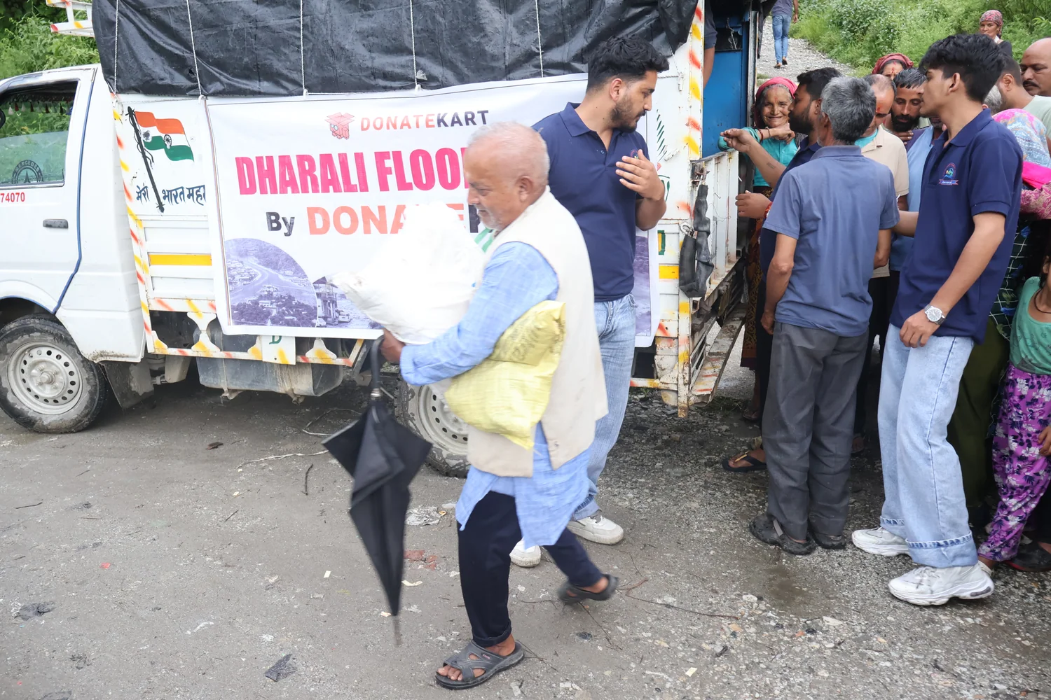 A ration sack is handed to a resident beside the relief vehicle.