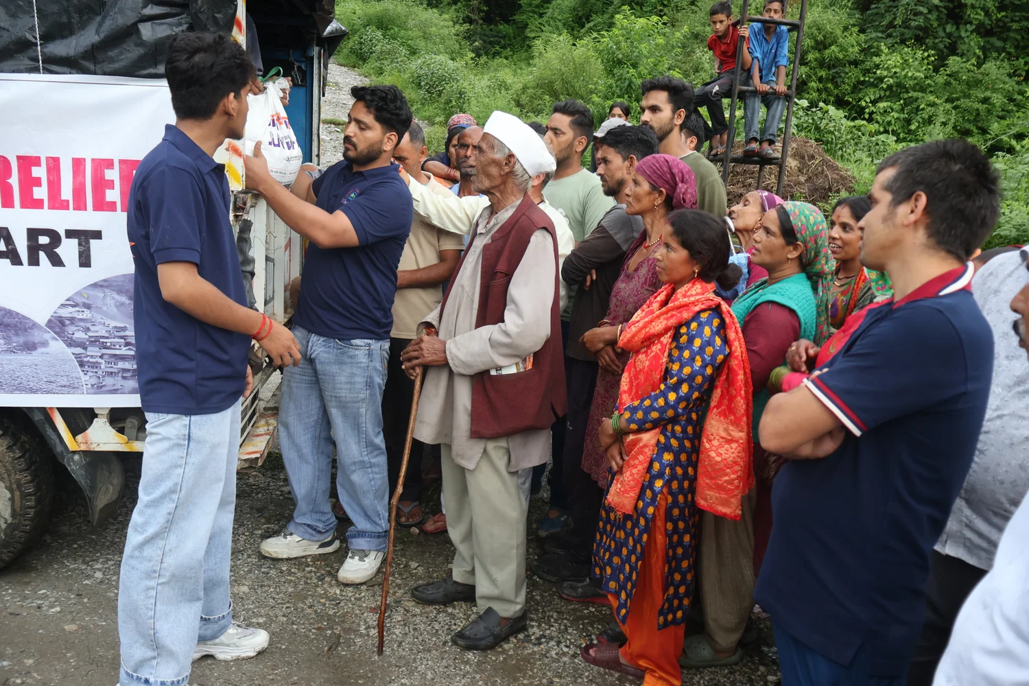 A resident receives food supplies as others wait near the distribution vehicle.