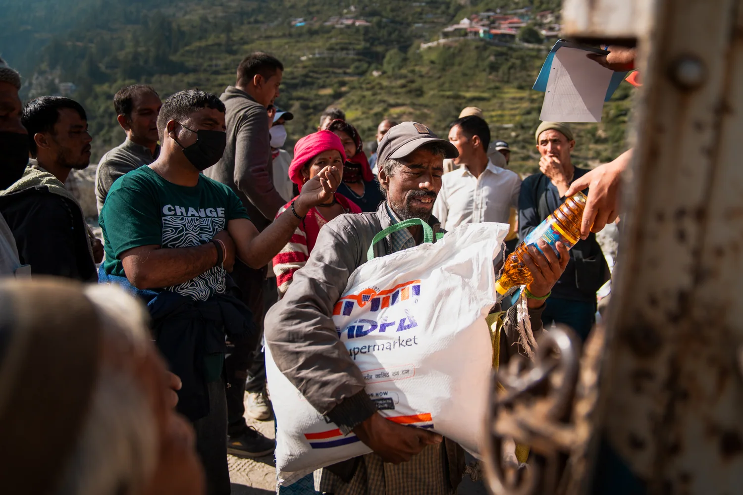 A resident holds food supplies beside the relief vehicle.