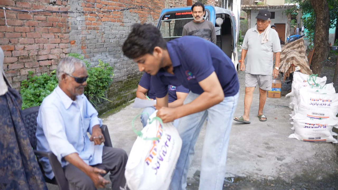 A ration bag is delivered beside a seated older resident.