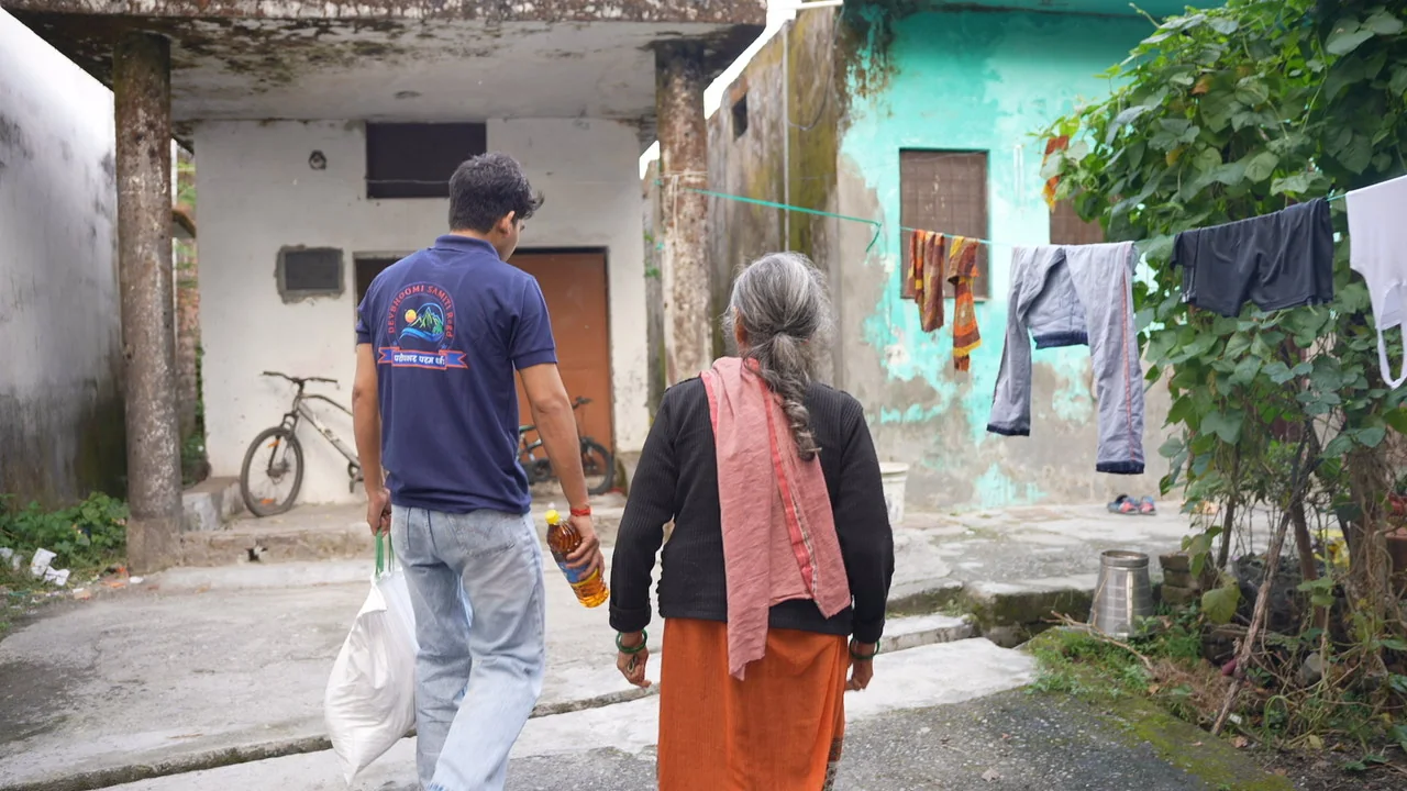 Walking alongside an older resident through a community lane.