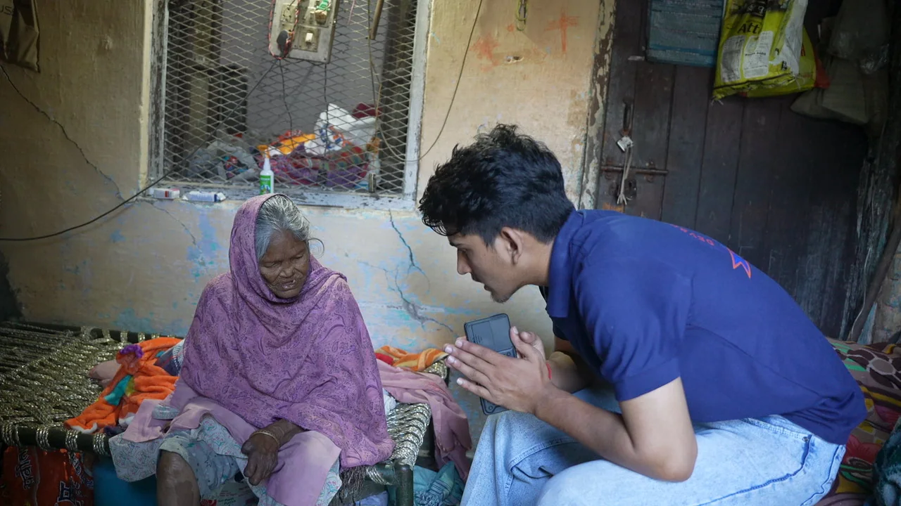 A team member sits and speaks with an older resident at home.