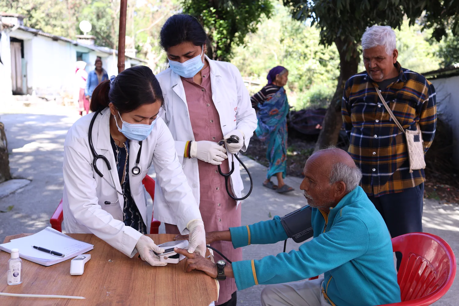 A seated man receives individual attention during the community health camp.