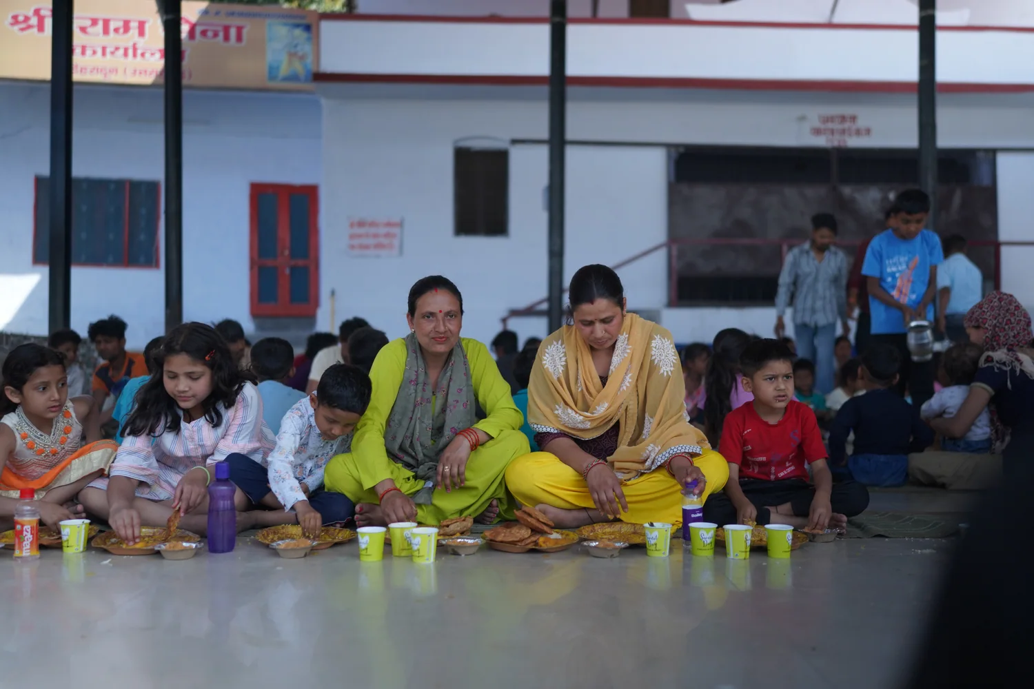 Children and adults sit together with their meal plates.