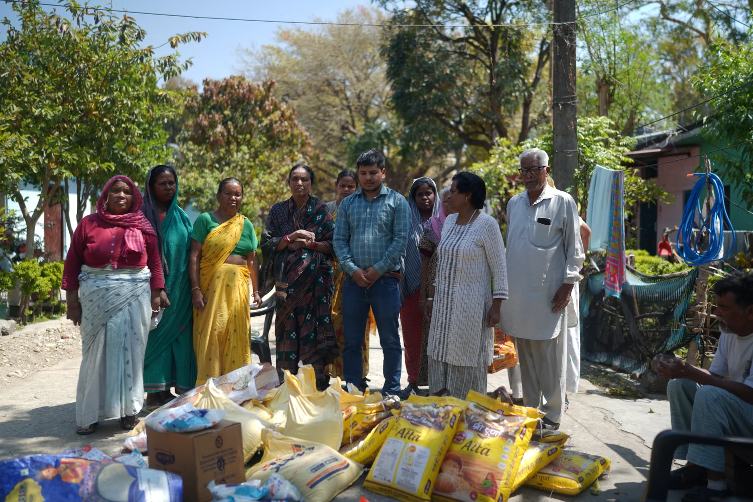 Community members and the team stand beside ration supplies arranged for handover.