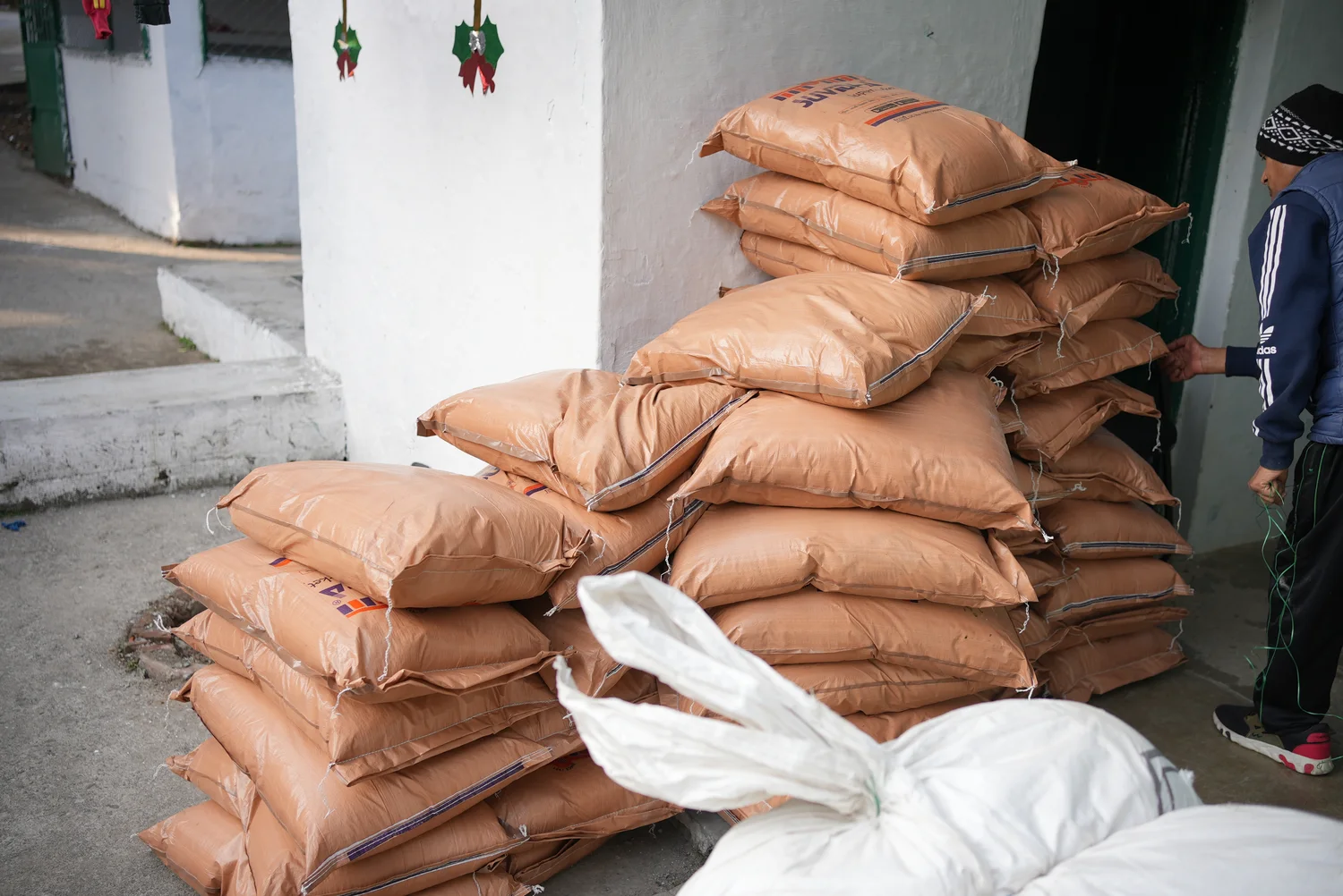 Ration sacks stacked beside a community building before collection.