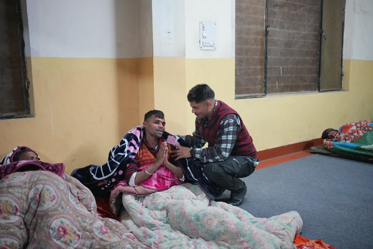 A team member speaks with a resident seated inside the shelter.