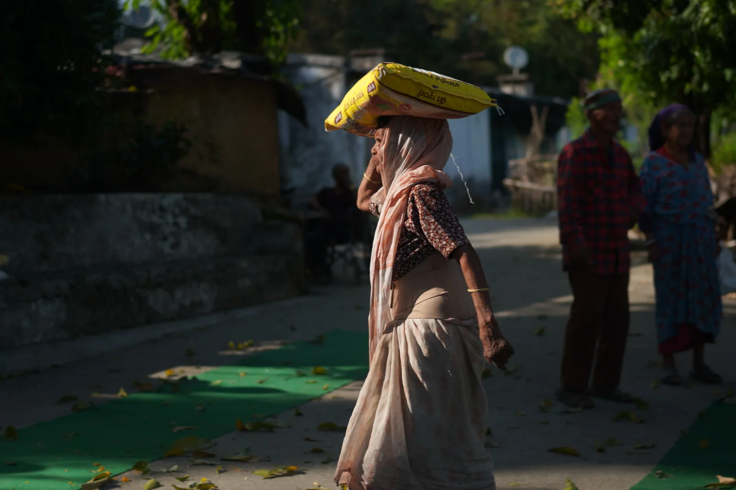 A woman carries ration supplies away from the courtyard.