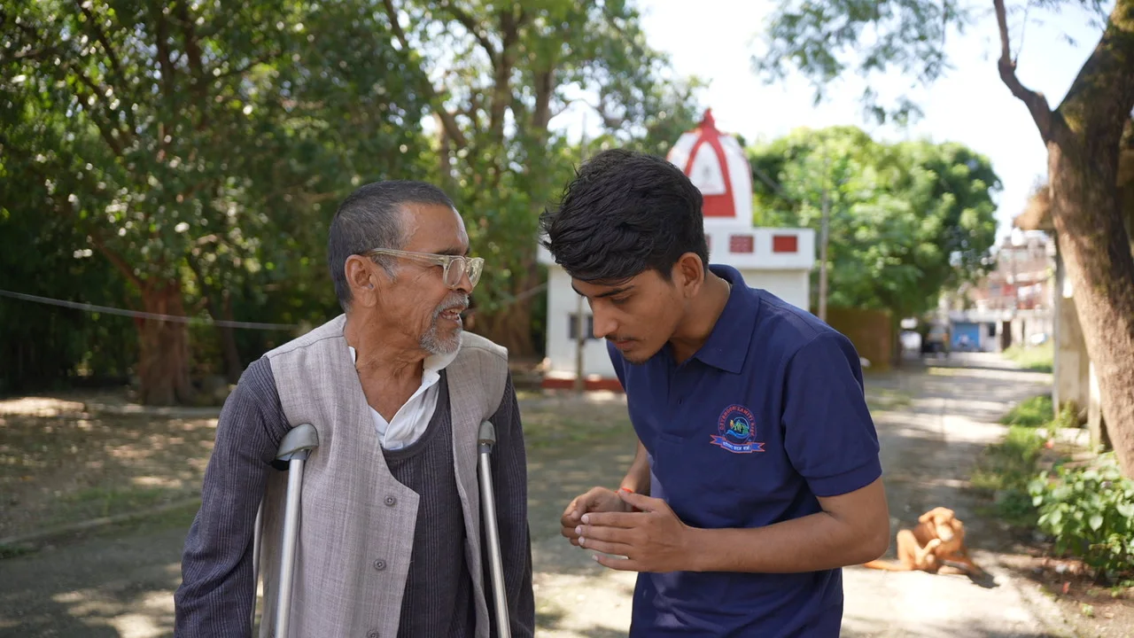 A visitor walks alongside an older resident during the outreach visit.
