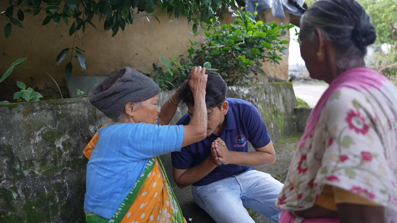 An older woman and a team member share a greeting.