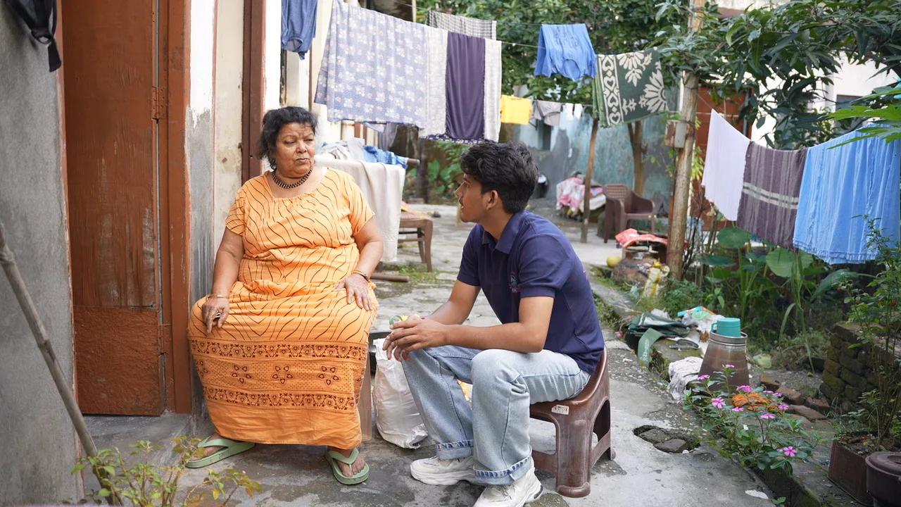 A team member sits beside a woman at her doorway.