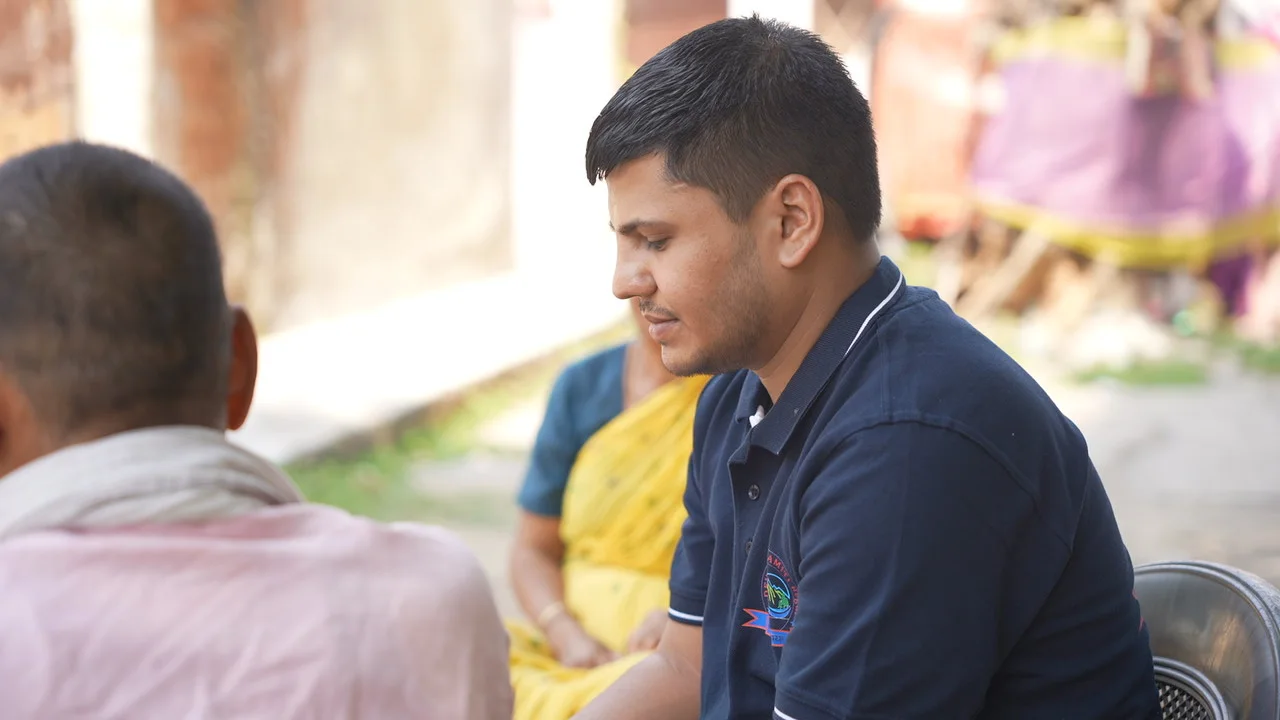 A team member speaks with residents seated in the courtyard.