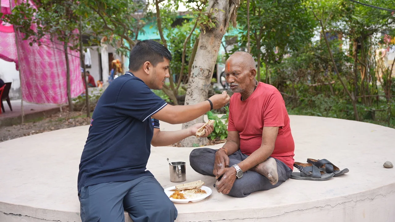 A team member provides mealtime assistance beside a resident’s home.