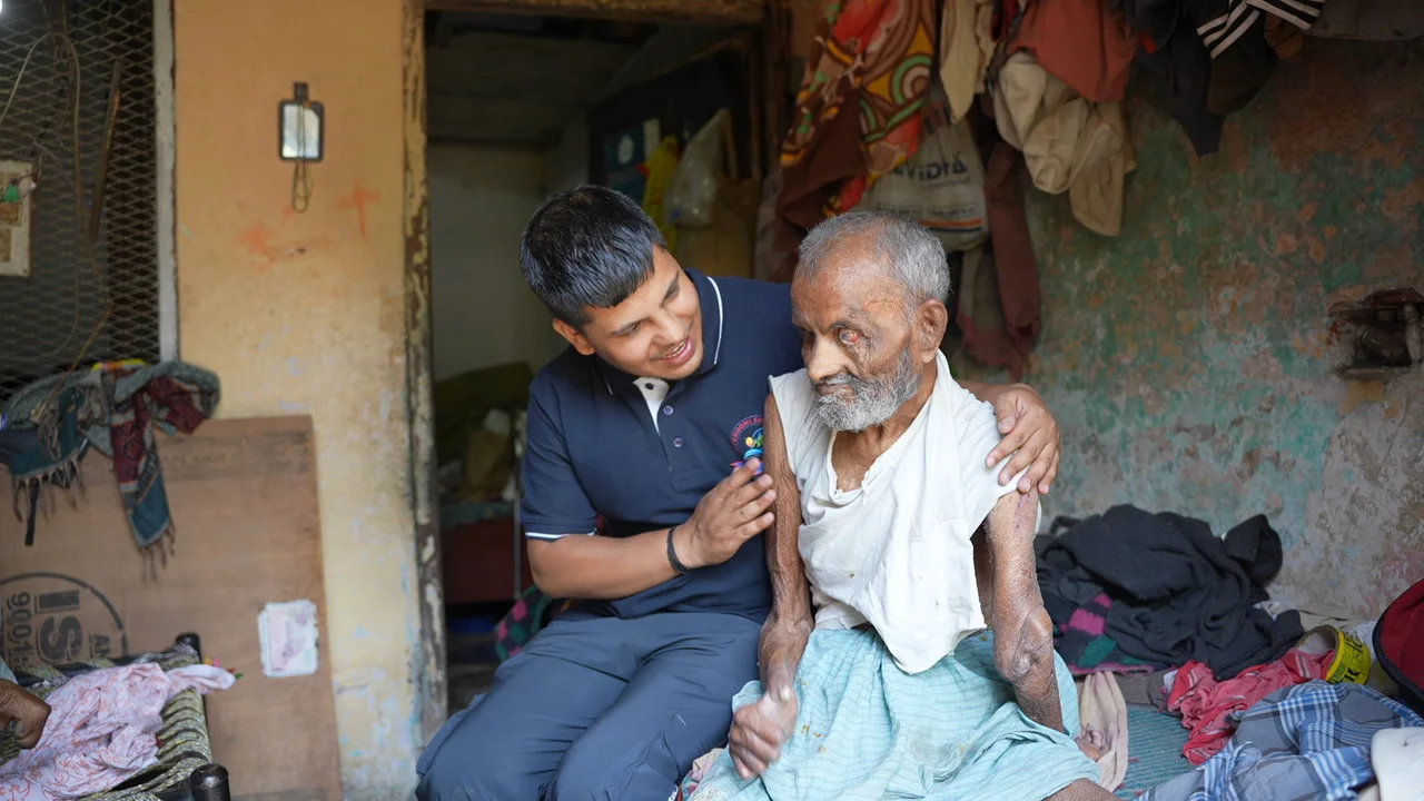 A team member sits beside an older resident during a home visit.