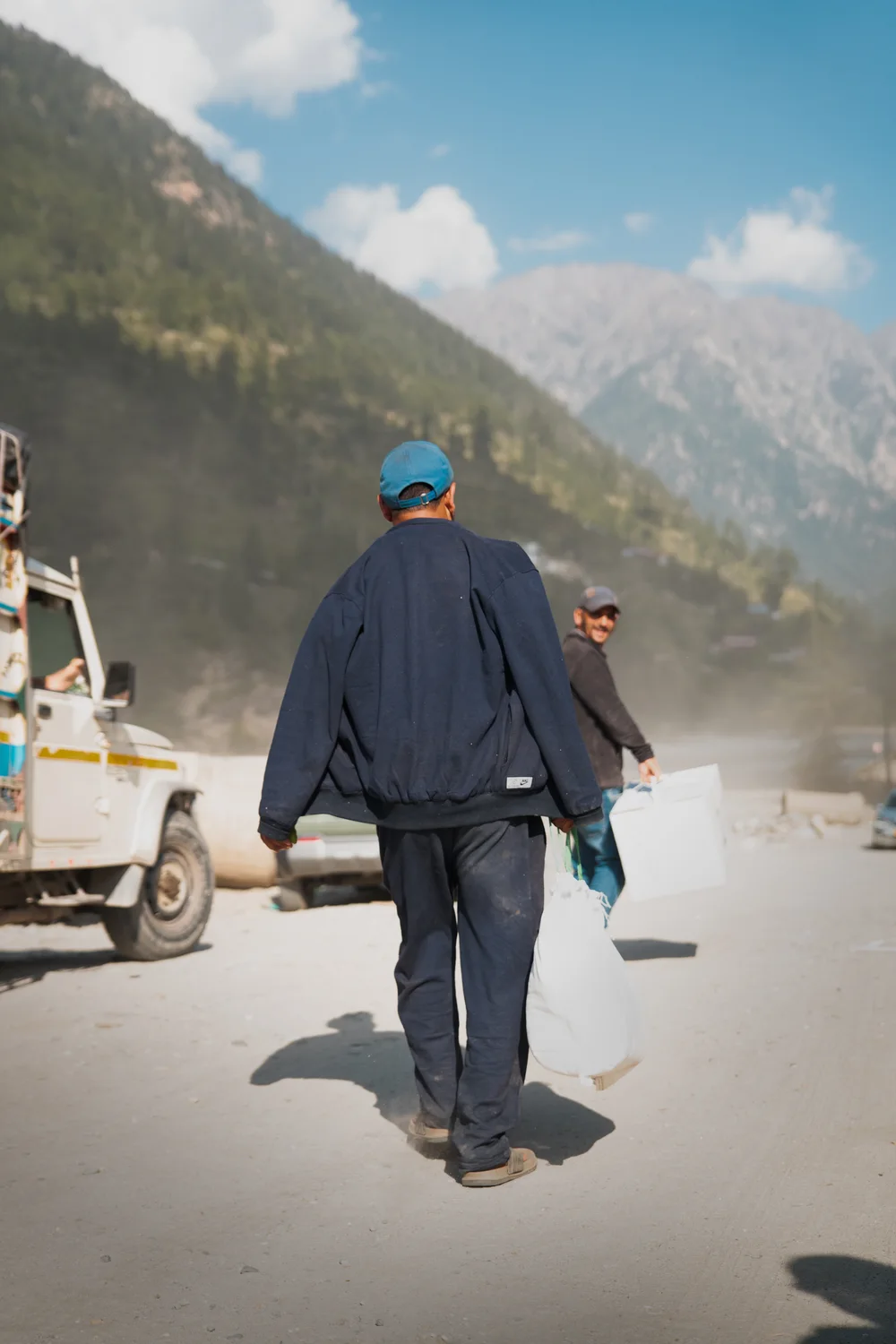 A resident carries containers along the road after collection.