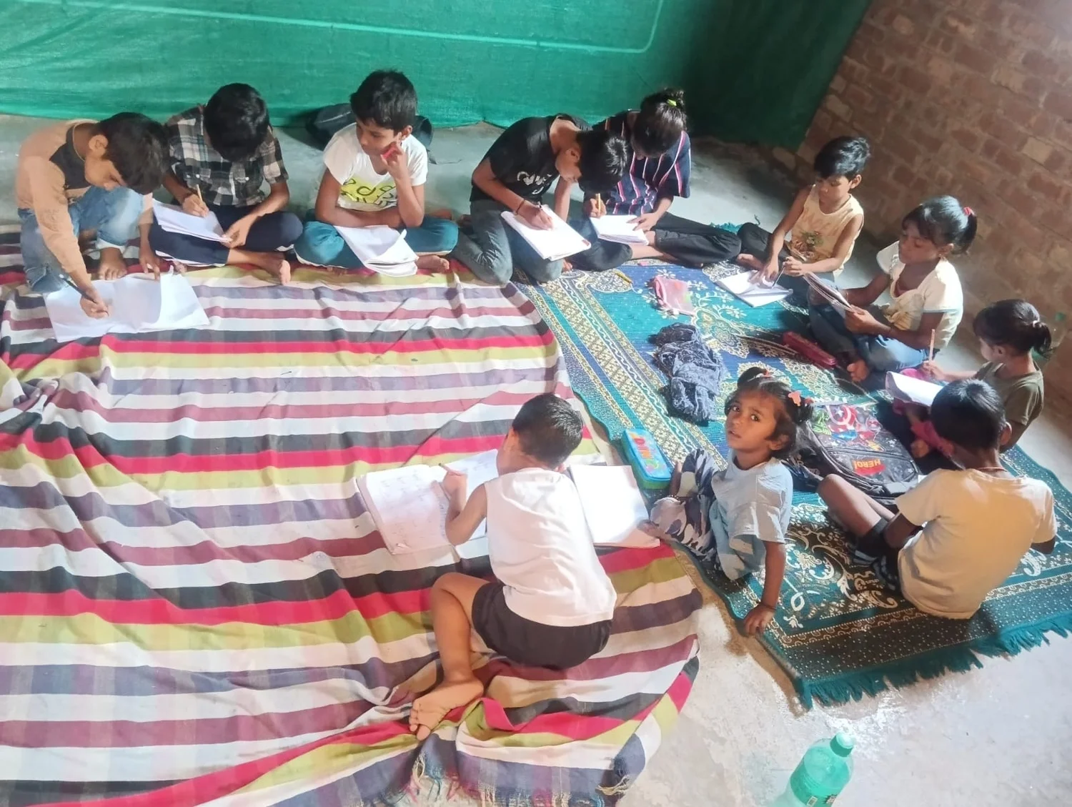 Children practise written work in their notebooks during a group session.