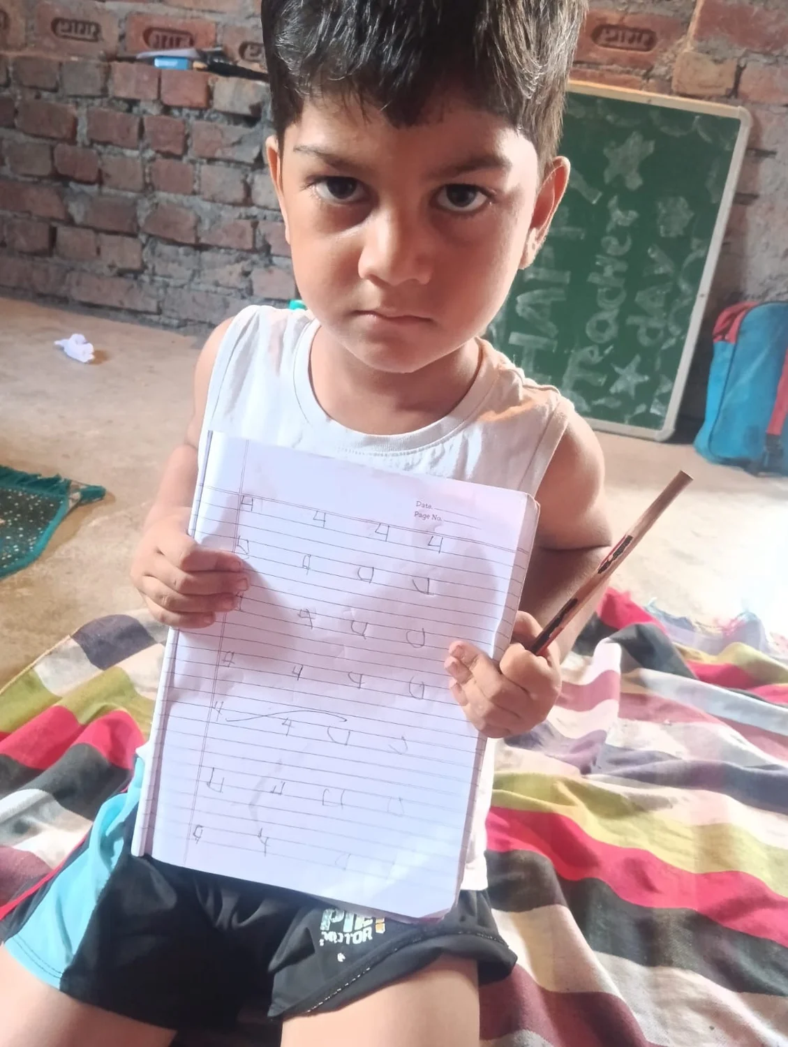 A young learner holds up a notebook page with letter-writing practice.