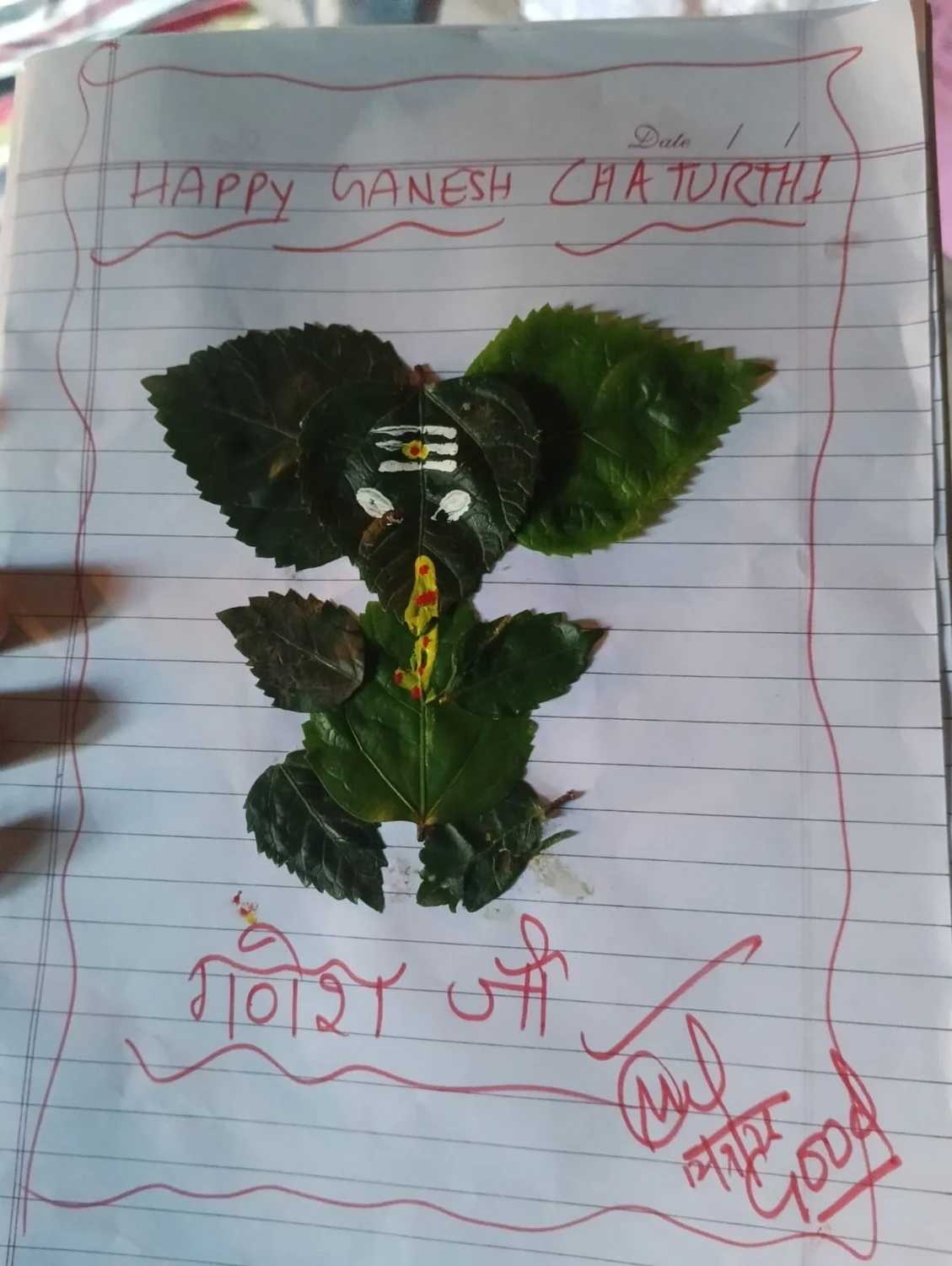 A close view of a leaf artwork with a handwritten Ganesh Chaturthi greeting.