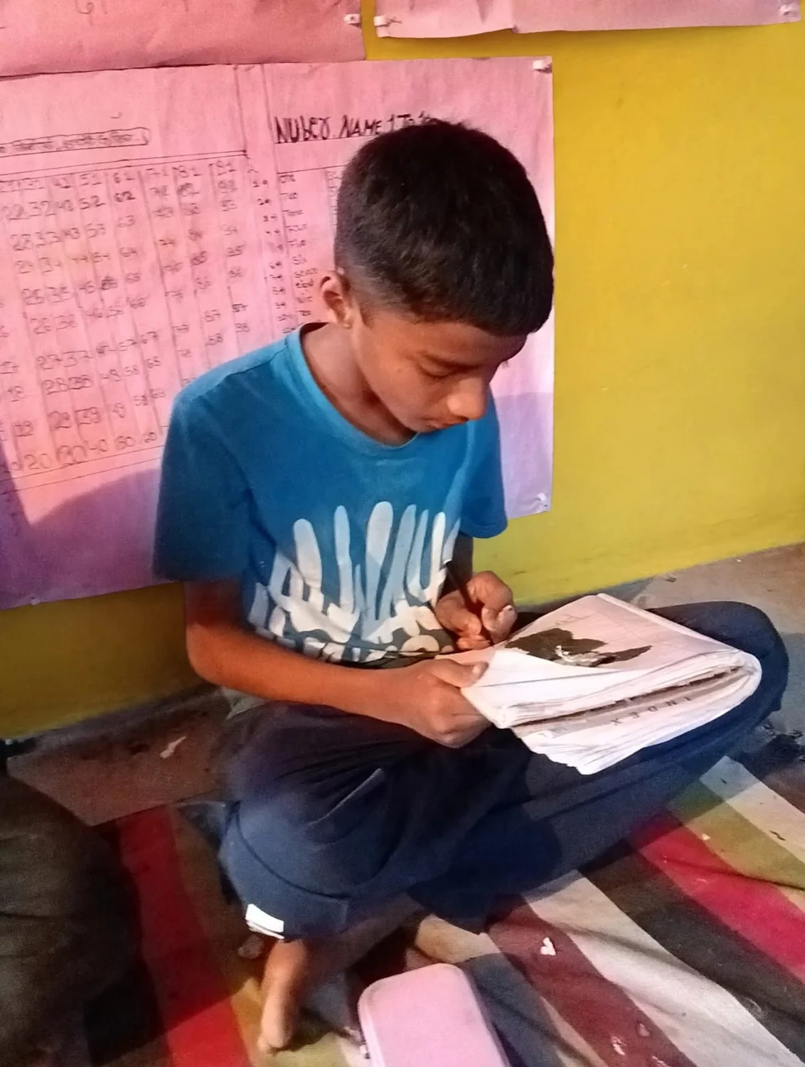 A learner adds painted details to an artwork on his notebook page.