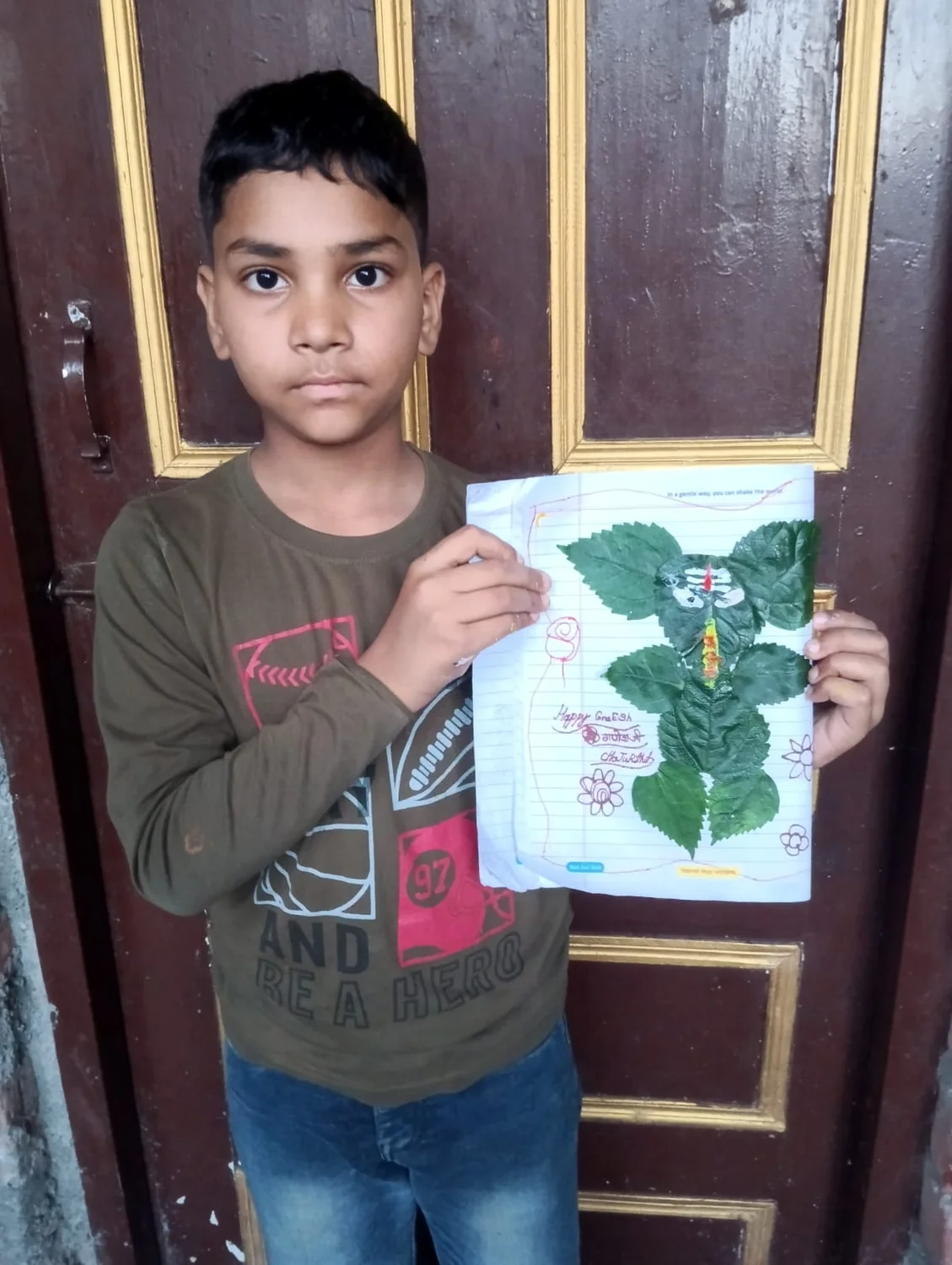 A learner holds a leaf artwork with hand-drawn decorations around it.
