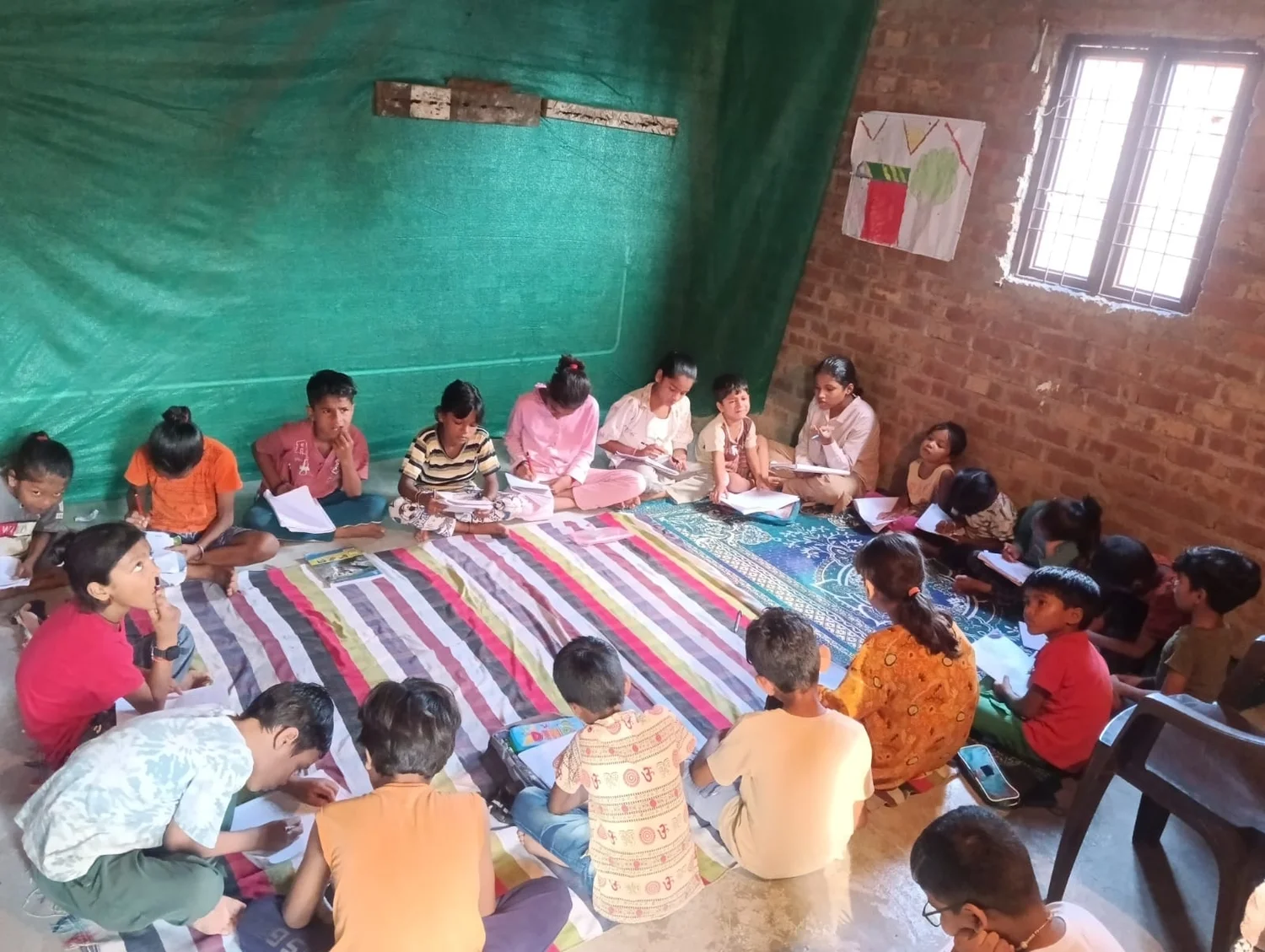 Children work in their notebooks around the shared community learning space.