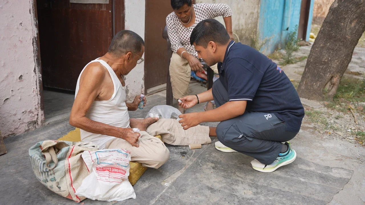 A Dev Bhoomi Samiti volunteer helping an older man outside his home
