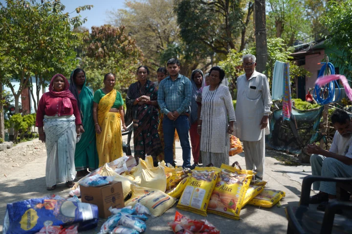 Dev Bhoomi Samiti team and residents with food supplies arranged in a courtyard