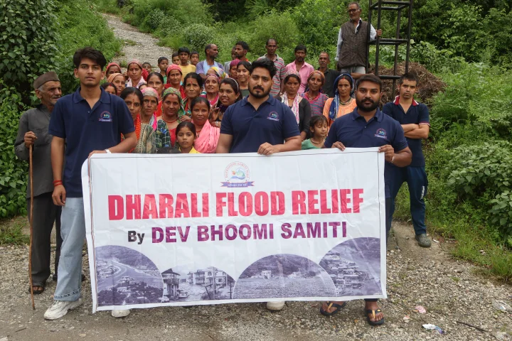 Community members and volunteers holding a Dharali Flood Relief banner outdoors