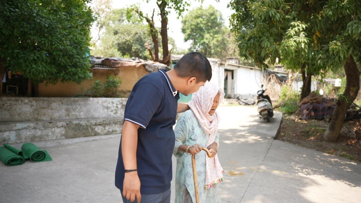 A volunteer standing beside an older woman in a courtyard