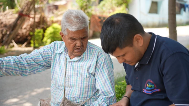 A volunteer assisting an older man during a community visit