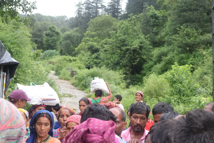Community members carrying relief supplies along a mountain path