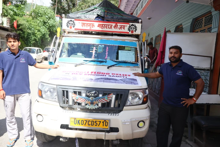 Dev Bhoomi Samiti team standing beside a vehicle loaded for relief work