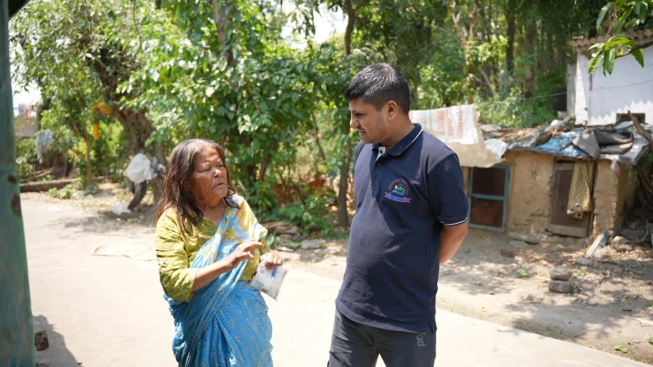 A volunteer walking with a woman through a shaded courtyard