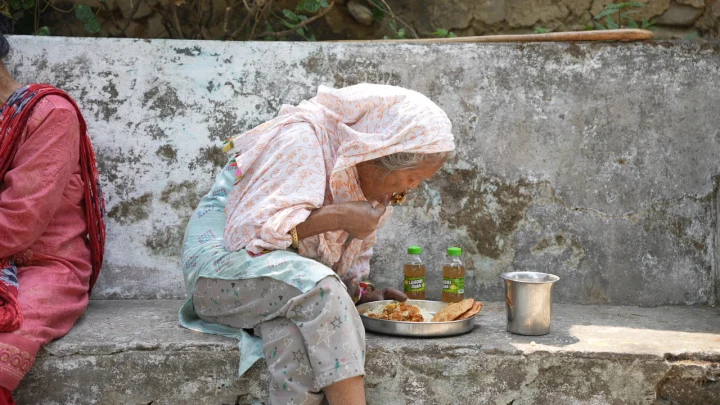 An older woman eating a meal outside her home