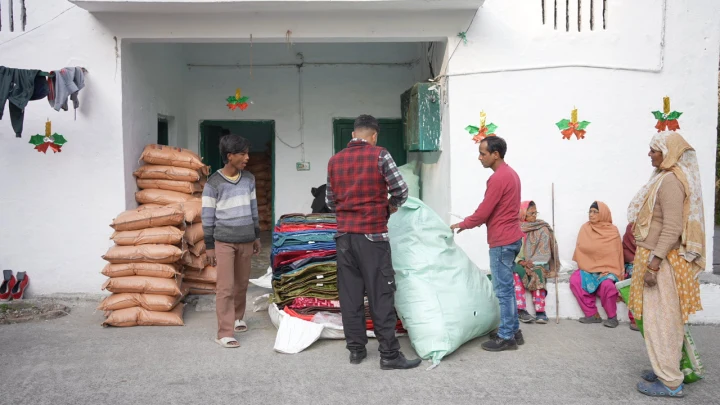 Dev Bhoomi Samiti volunteers with sacks of food supplies outside a community home