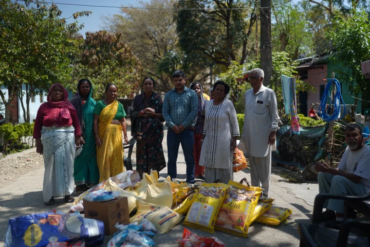 Community members standing beside ration bags and essential supplies