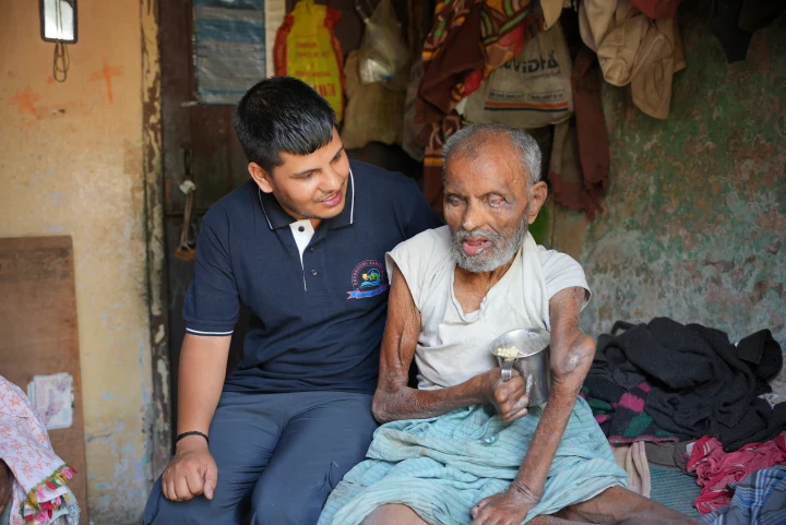 An older man and a Dev Bhoomi Samiti volunteer seated together
