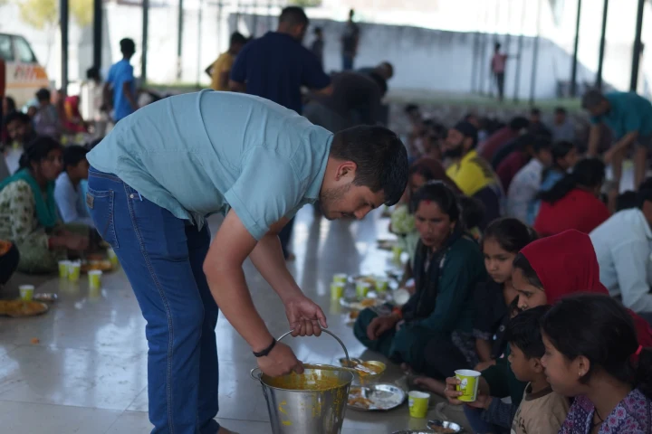 A volunteer sharing freshly served food with children at a community meal