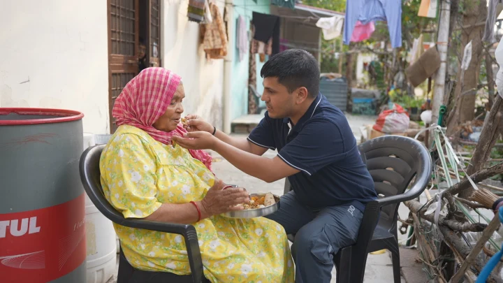 A volunteer sharing a meal with a woman seated in a courtyard