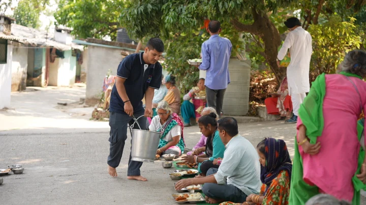 Volunteers distributing meals to a seated group of community residents
