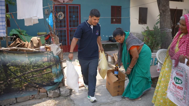 A volunteer handing a bag of supplies to a woman outside her home